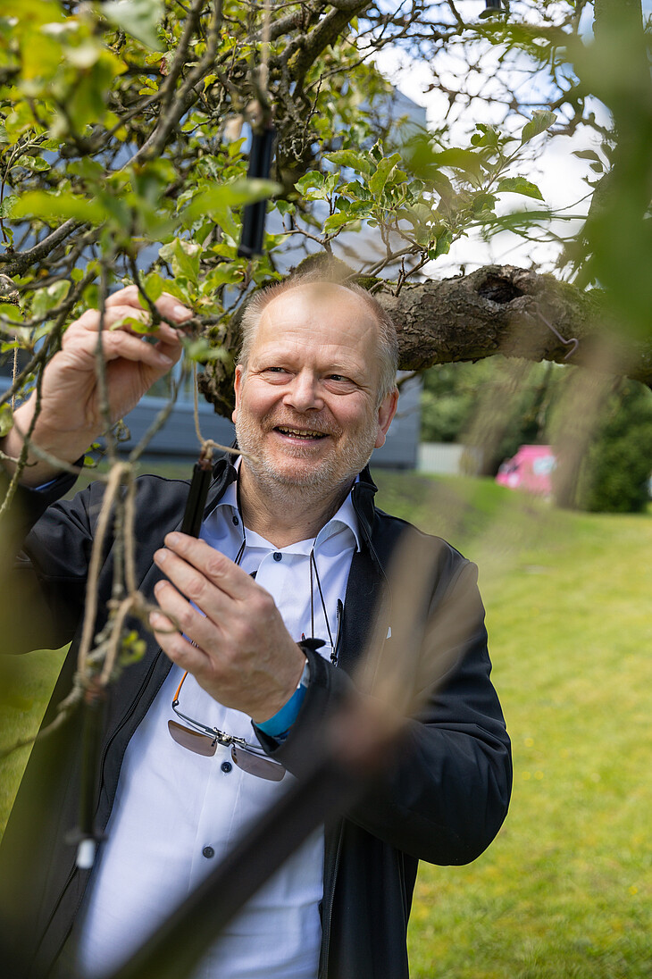 Ein Mann beim Aufhängen einer kleinen Kartusche an den Ast eines Baumes